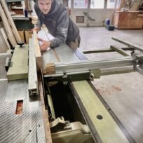 Le menuisier passe une planche dans la scie à format