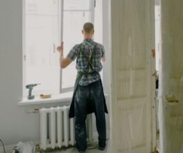 un menuisier installe de nouvelles fenêtre et des portes intérieures en bois mouluré