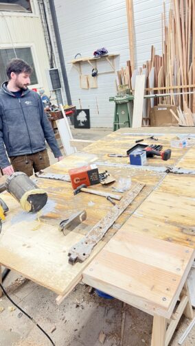 porteanciennereparation Le menuisier à côté de la porte en cours de rénovation dans notre atelier